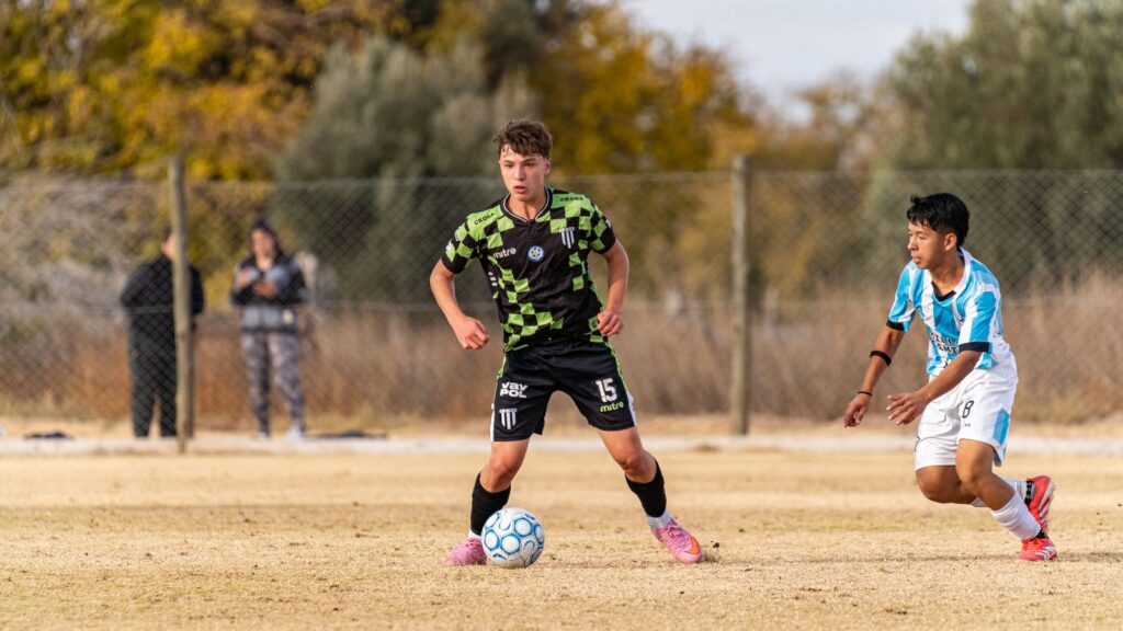 Teen boy in a soccer jersey dribbling the ball during a youth soccer game